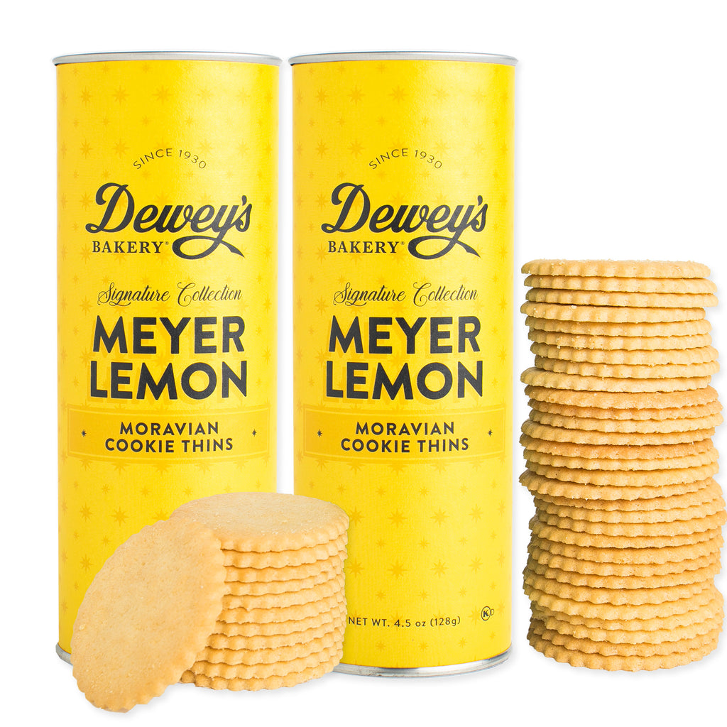 Two yellow cans of Dewey's Bakery Meyer Lemon Moravian Cookie Thins with cookies in front.