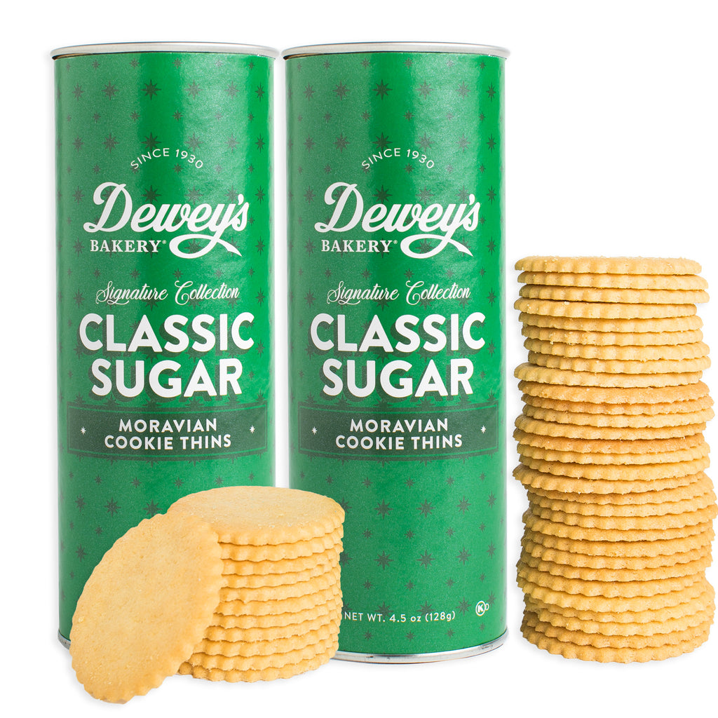 Two green cans of Dewey's Bakery Classic Sugar Moravian Cookie Thins with cookies in front on a white background.